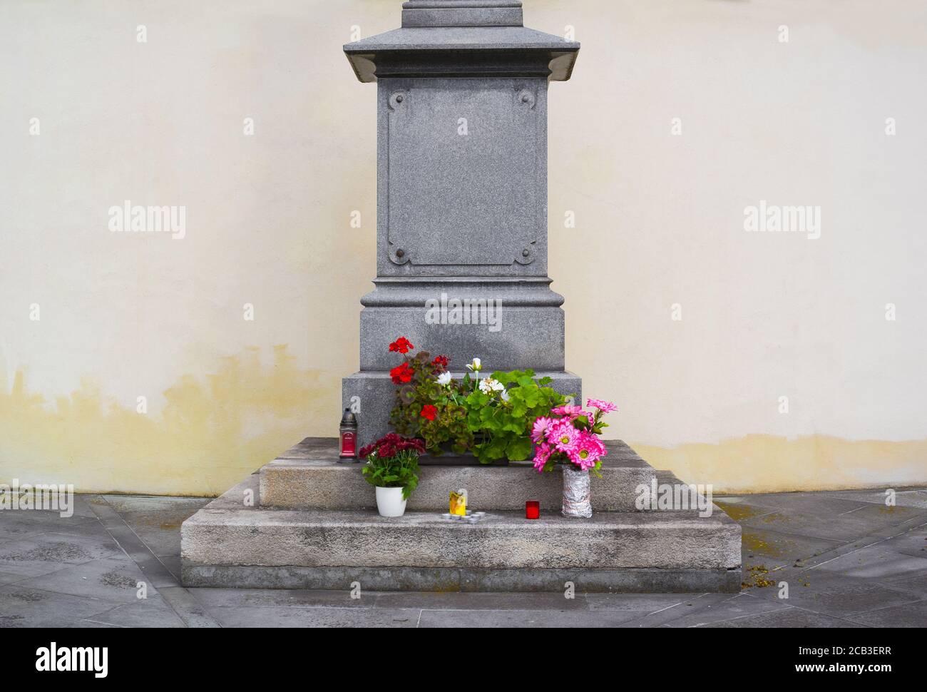 Detail des Sockels. Kerzen, Blumen, Blumenstrauß als Ausdruck von Gedenken, Verherrlichung oder Ehre. Leere Wand im Hintergrund als Kopierbereich Stockfoto