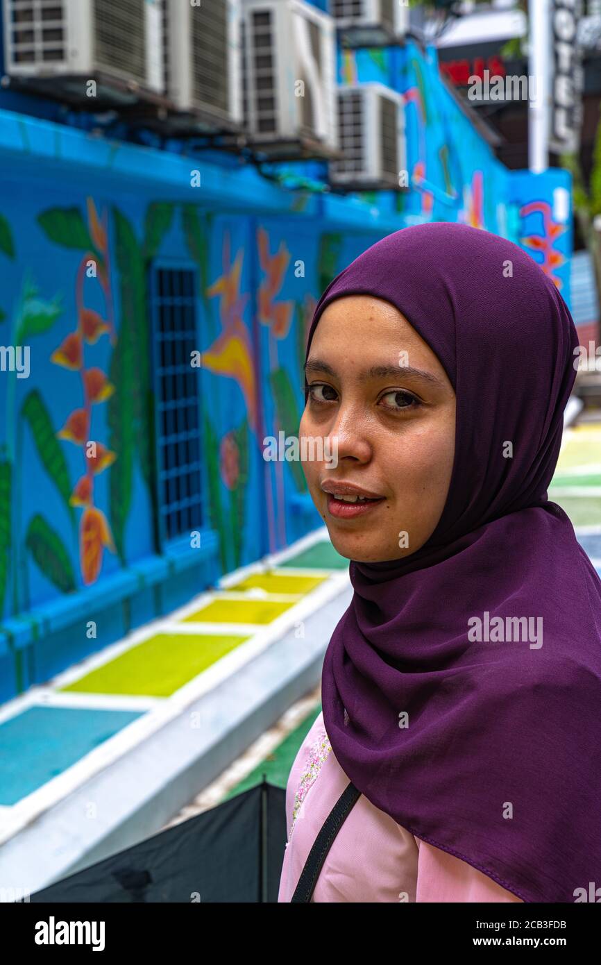 Kuala Lumpur/Malaysia/24 May 2020: Portrait eines jungen schönen muslimischen Mädchens mit purpurem Kopftuch und rosa Kleid in Jalan Alor, Malaysia Stockfoto