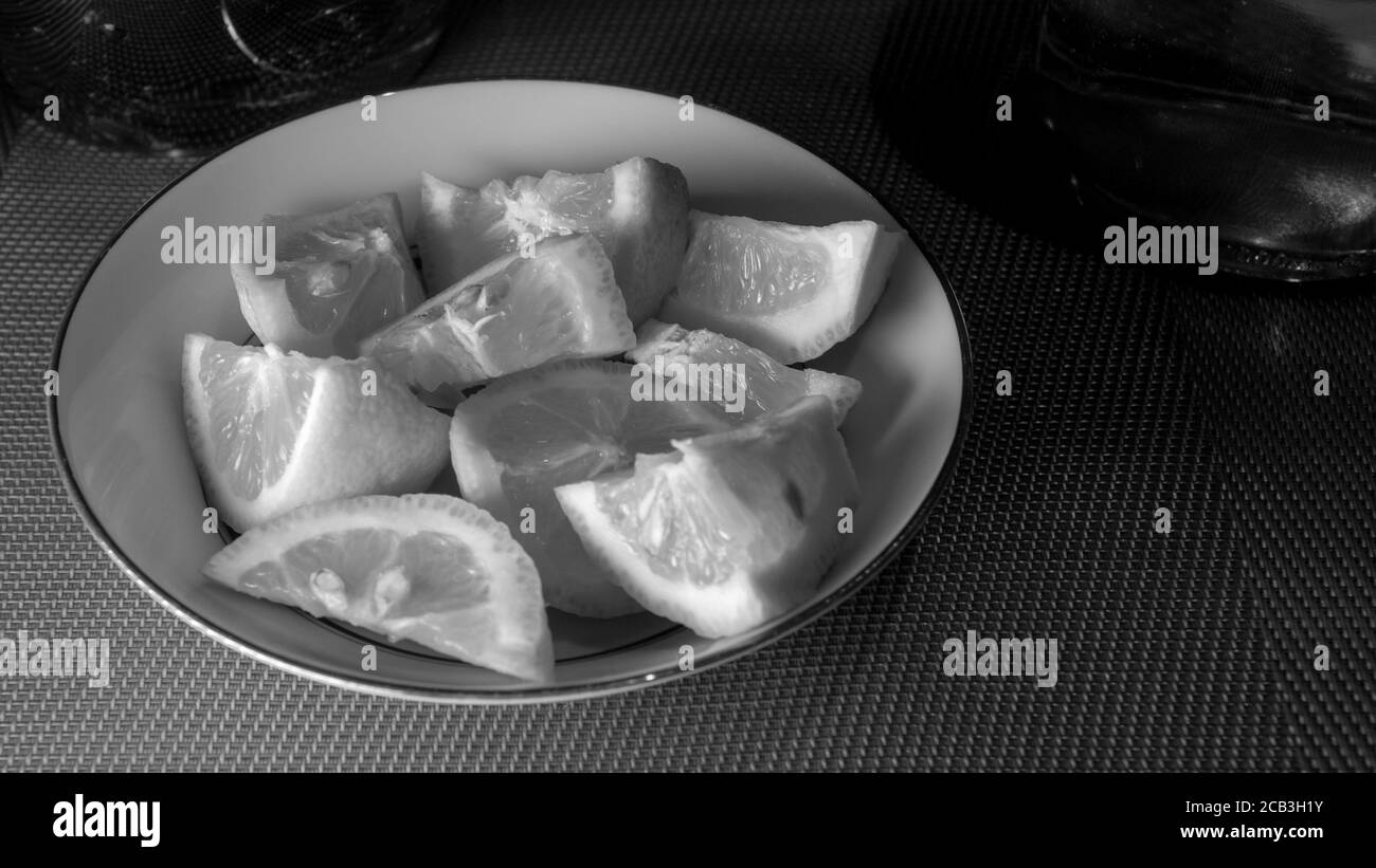 Geschnittene Zitrone in einer Schüssel in schwarz und weiß gestapelt bereit, als Begleitung für eine Mahlzeit serviert werden. Es gibt stimmungsvolle Beleuchtung mit Kontrast. Stockfoto