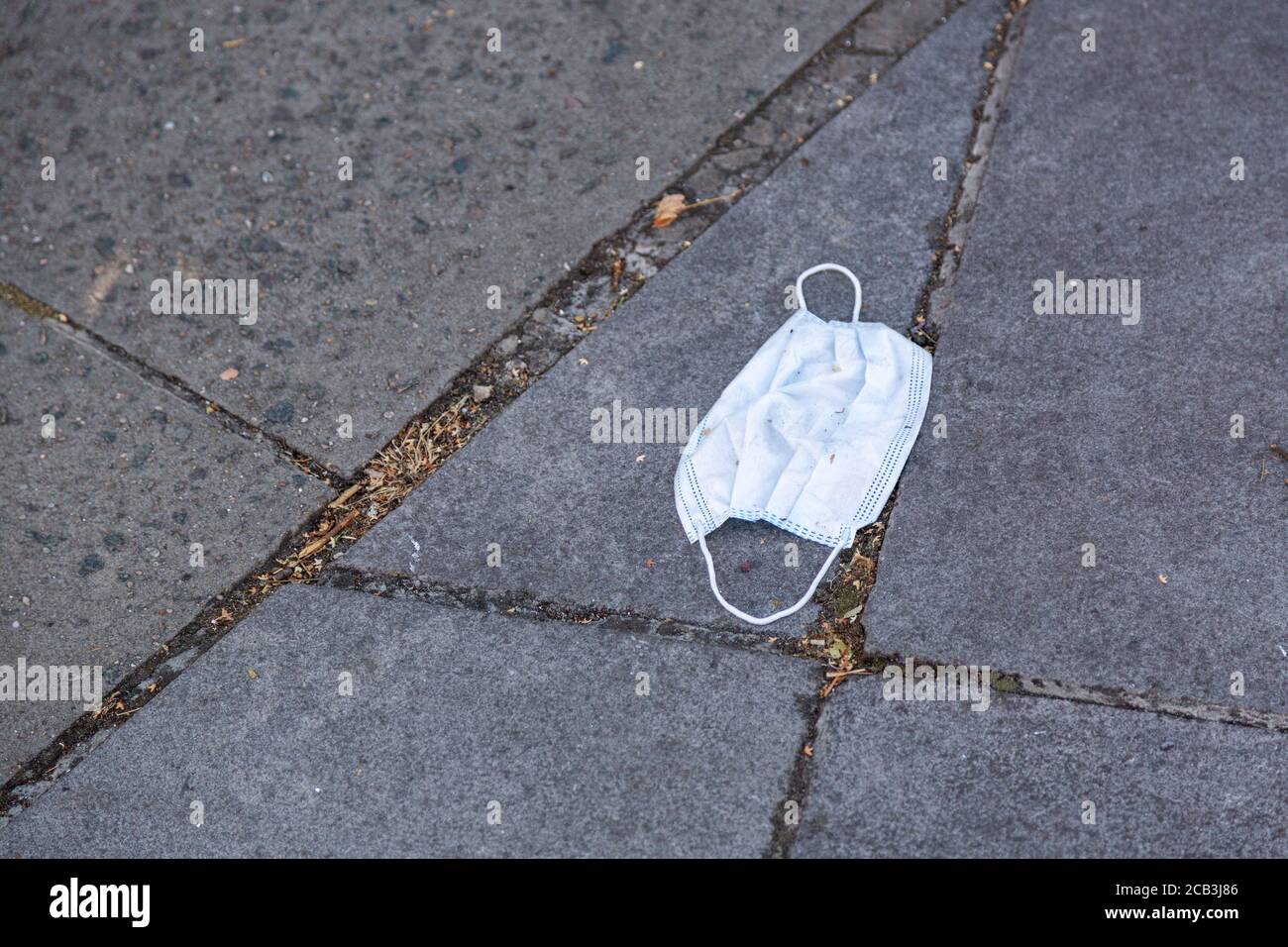 Eine weggeworfene Gesichtsmaske auf der Straße Stockfoto