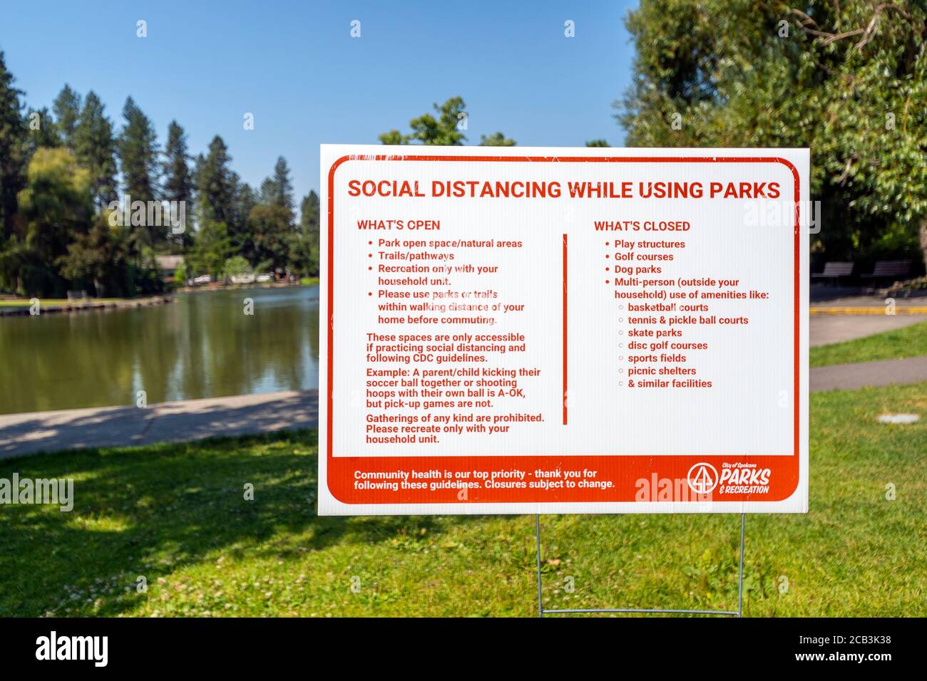 Ein Stadtparkschild in Spokane Washingtons öffentlichem Manito Park bietet soziale Distanzierungsinformationen und Richtlinien für die Gesundheit in Spokane, Washington. Stockfoto