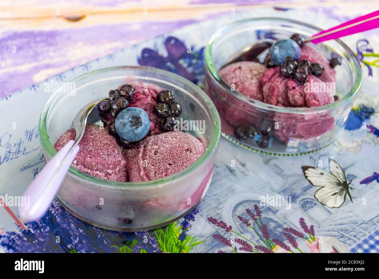 Köstliches hausgemachtes Lavendeleis in einer Glastasse mit Heidelbeeren und Waldbeeren, aus nächster Nähe Stockfoto