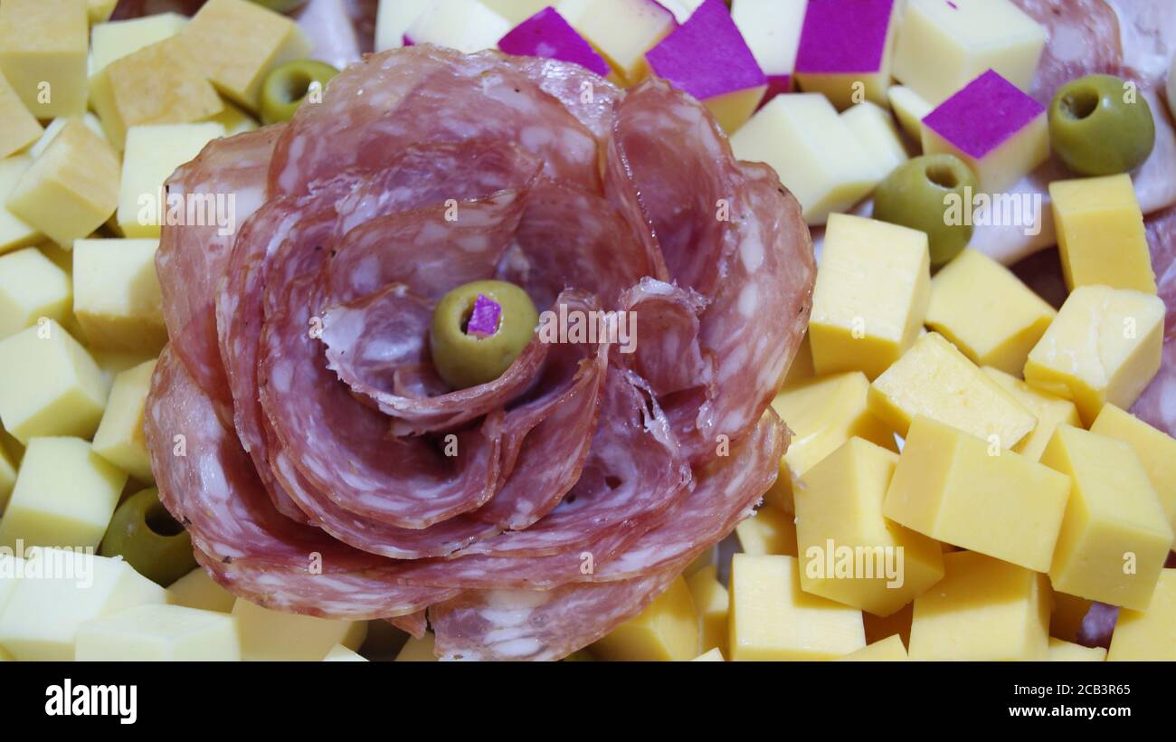 Salami. Aufschnitt-Tafel mit rosafarbenförmiger Salami, mit verschiedenen Käsesorten, grüne Oliven im Foto-Zoom Stockfoto