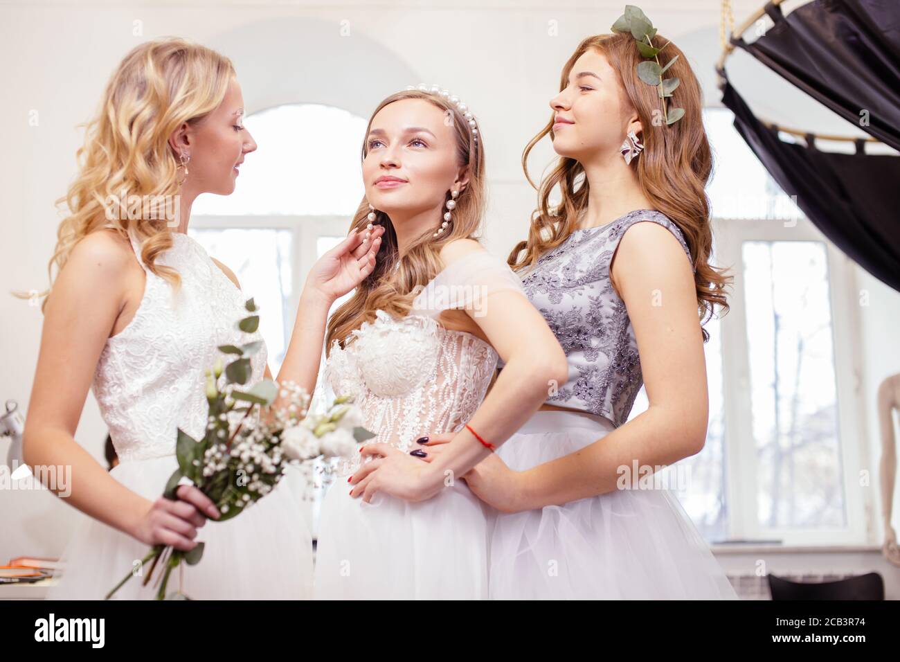 Junge kaukasische Freunde wählen, versuchen auf Hochzeitskleider im Salon, schöne Frauen für die Hochzeit vorbereiten, zu feiern, träumen Braut zu sein Stockfoto