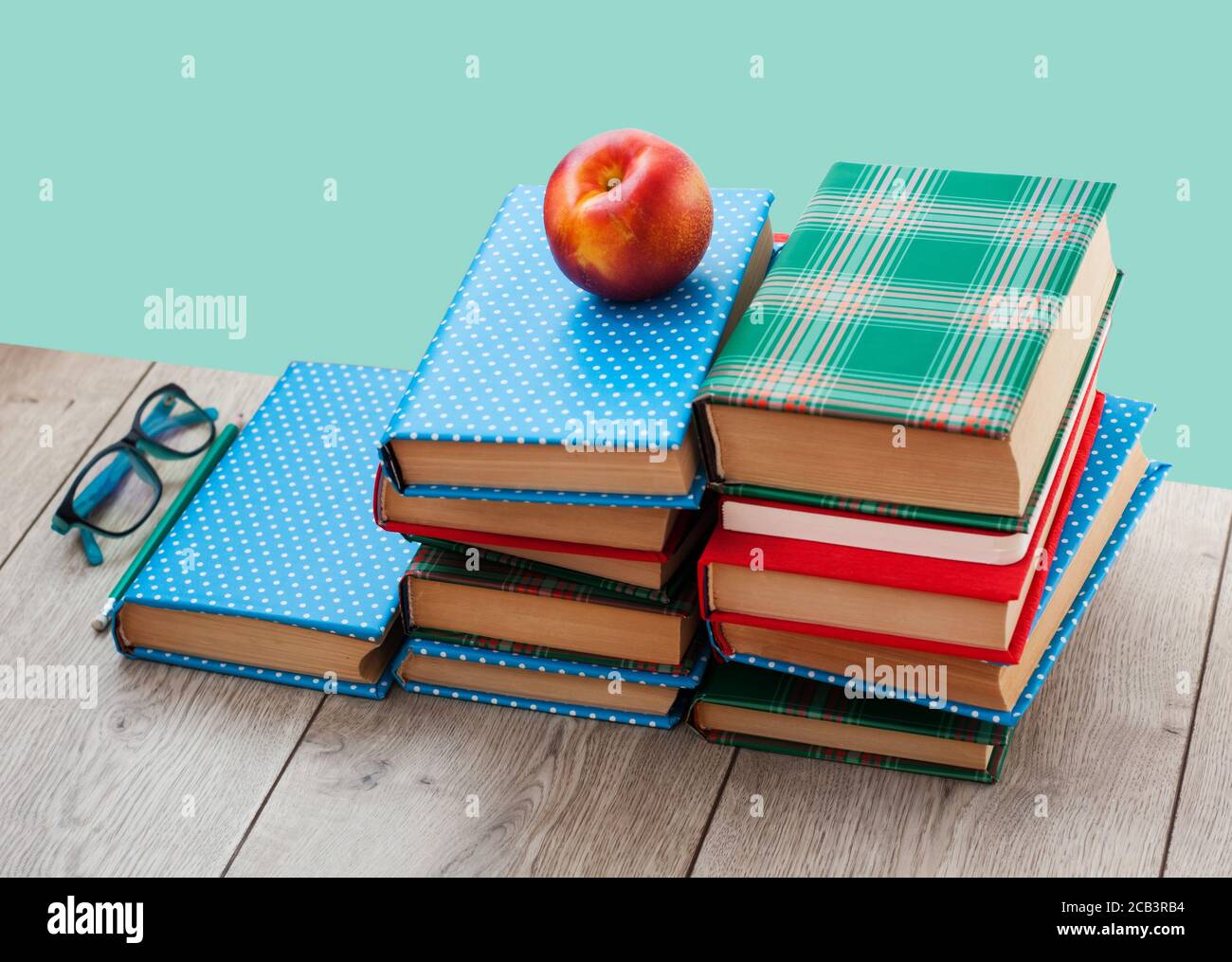 Zurück in die Schule, Stapel von Büchern in bunten Abdeckungen und Pfirsich auf Holztisch mit grünen Minze Hintergrund. Fernhausbildung.Quarantine Konzept der s Stockfoto