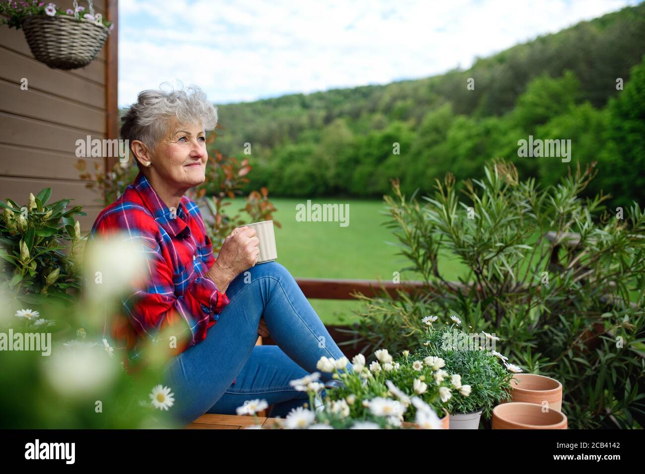 Ältere Frau mit Kaffee sitzen auf der Terrasse im Sommer, Ruhe. Stockfoto