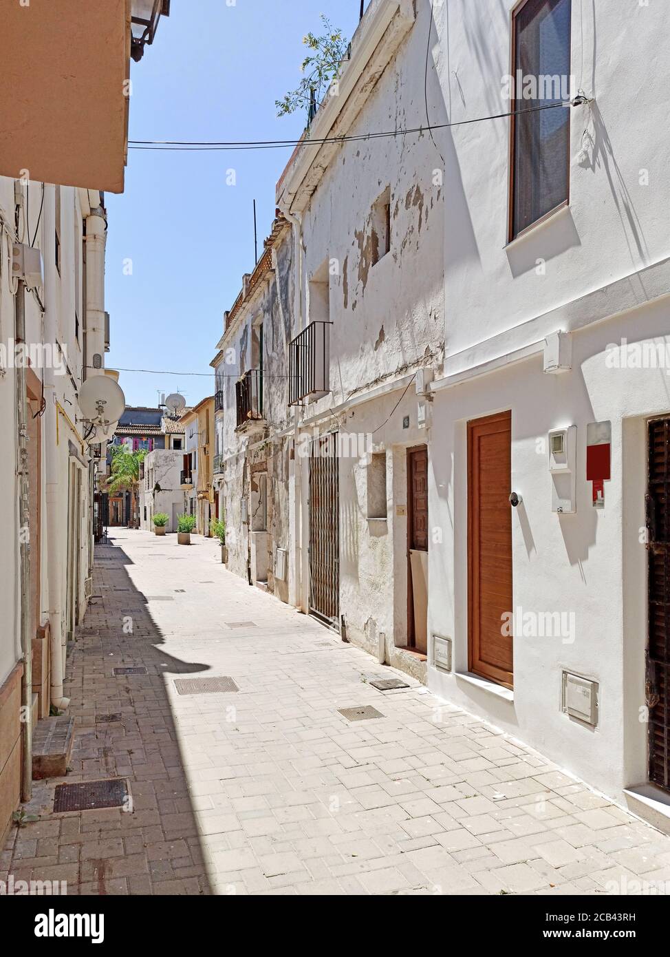 Charmante schmale, weiß getünchte Straße während des heißen Sommertages der touristischen spanischen Stadt Denia. Valencianische Gemeinschaft, Provinz Alicante, Stockfoto