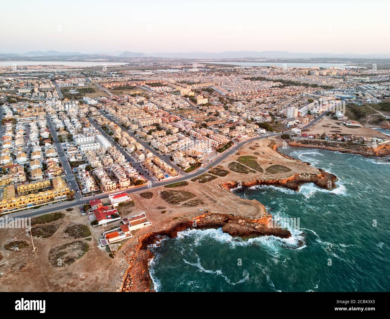 Luftpanoramabo von Torrevieja Stadtbild, felsige Küste Mittelmeer bei Sonnenaufgang, Salzsee oder Las Salinas, Bildansicht von oben. Pro Stockfoto