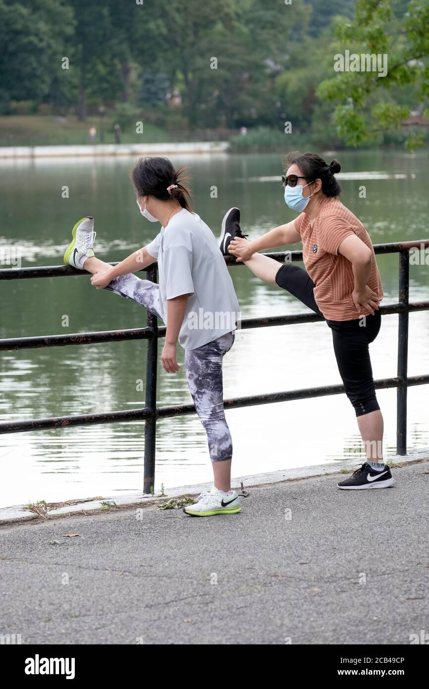 Zwei asiatisch-amerikanische Frau schlagen einen ähnlichen Elch beim Stretching vor Morgenübungen. In Kissena Park, Flushing, New York City Stockfoto