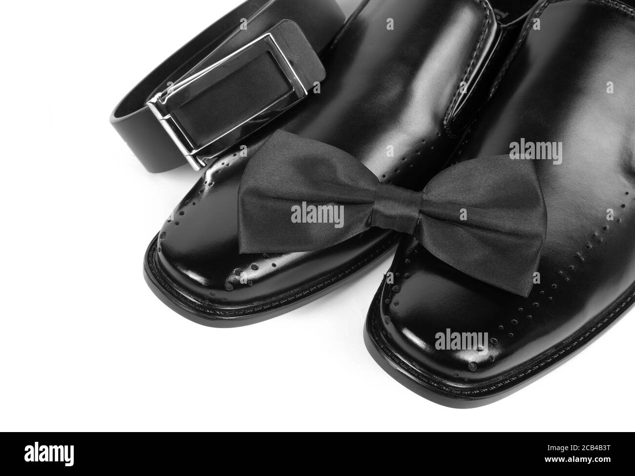 Nahaufnahme von schwarzen männlichen Schuhen, Fliege und Gürtel auf weißem Hintergrund Stockfoto