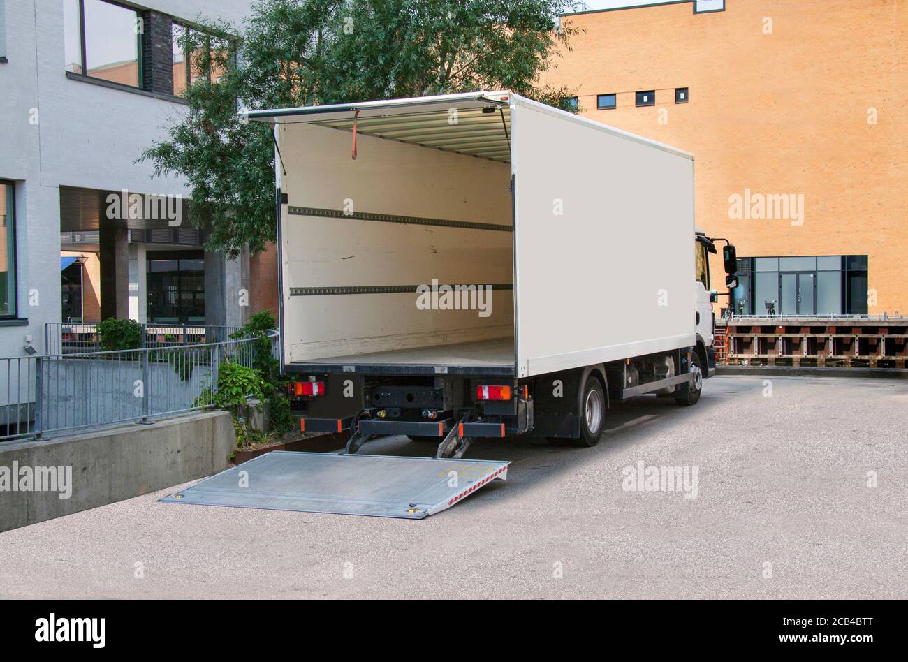 Weißer Lieferwagen mit geöffneter Heckklappe vor einem Bürogebäude. Speicherplatz kopieren. Stockfoto