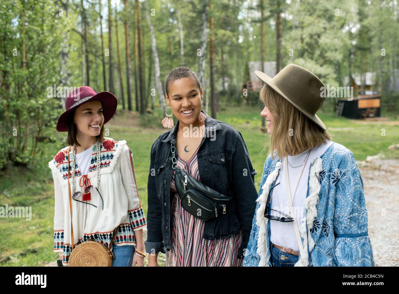 Positive junge interracial Frauen in Hippie-Outfits zu Fuß zusammen, während Urlaub auf dem Campingplatz genießen Stockfoto