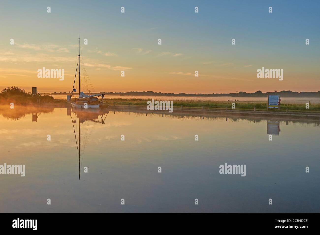 Potter Heigham, Norfolk Broads und ein Segelboot, das während eines nebligen Sommersonnenaufgangs auf dem Fluss Thurne festgemacht wurde. Stockfoto