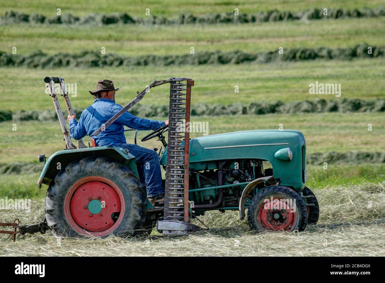 Trossingen, Deutschland, 06/23/2020 Biobauer mit seinem alten Kramer Traktor bei der Heuernte. Stockfoto