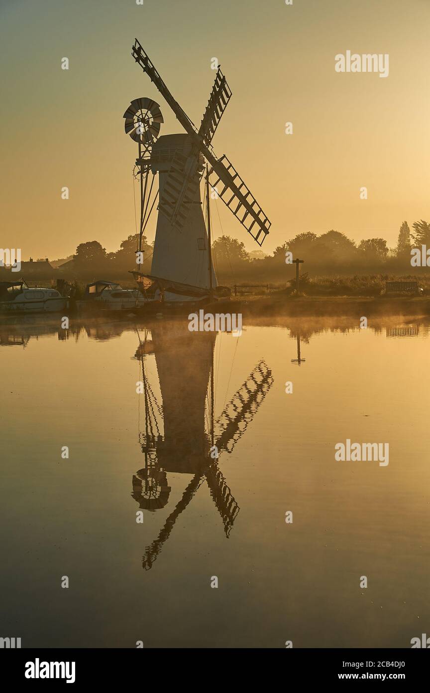 Thurne Dyke Entwässerung Windmühle Norfolk, spiegelt sich in der Fluss Thurne bei Sonnenaufgang mit Booten am Flussufer festgemacht. Stockfoto Thurne Dyke Entwässerung Windmühle Norfolk, spiegelt sich in der Fluss Thurne bei Sonnenaufgang mit Booten am Flussufer festgemacht. Stockfoto