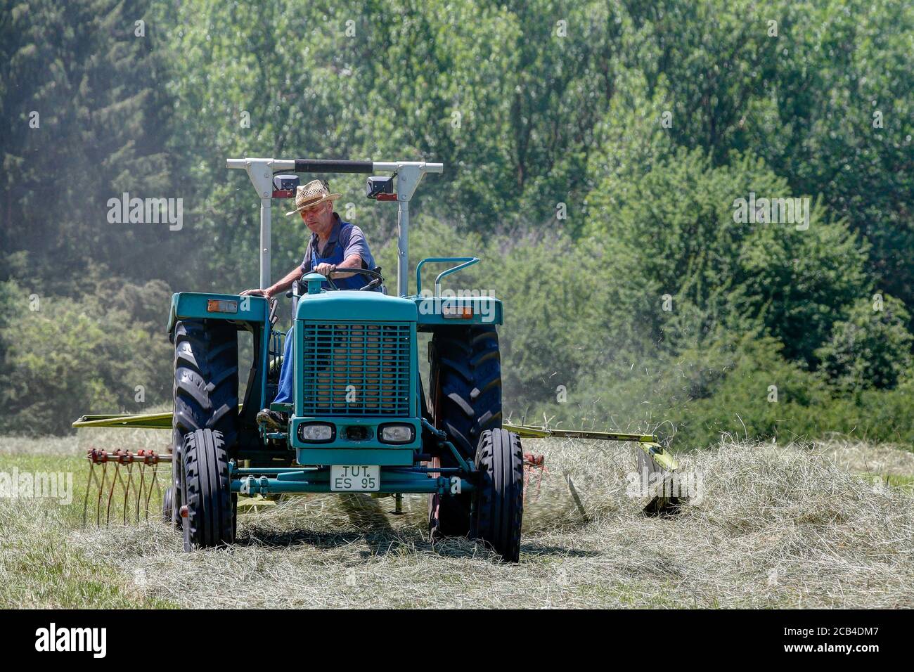 Trossingen, 25. Juni 2020. Bio-Bauer mit seinem alten Traktor und Rechen arbeiten das Heu. Der Schwad wird benötigt, um das Heu weiter zu verarbeiten. Stockfoto