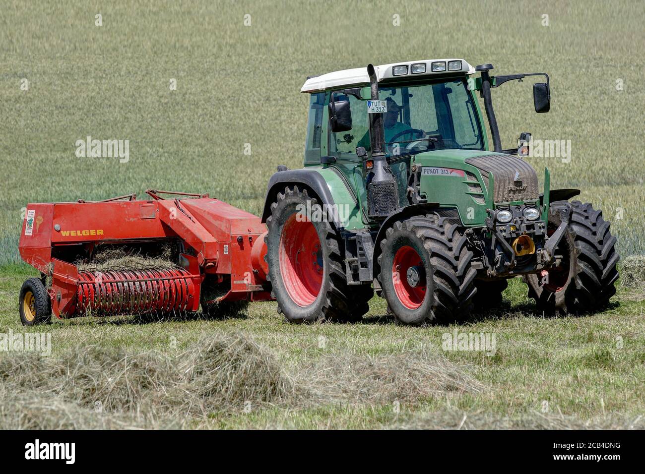 Trossingen, 25. Juni 2020. Moderner Fendt 313 Traktor auf dem Feld, der mit einer 40 Jahre alten Welger-Ballenpresse Heu in Ballen presst. Stockfoto