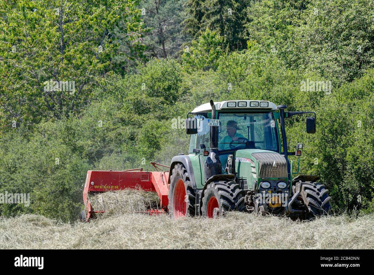 Trossingen, 25. Juni 2020. Moderner Fendt 313 Traktor auf dem Feld, der mit einer 40 Jahre alten Welger-Ballenpresse Heu in Ballen presst. Stockfoto