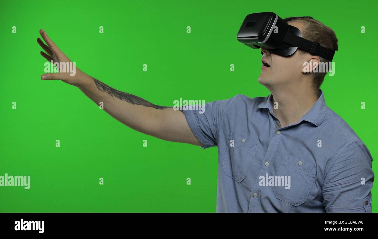 Mann mit VR-Technologie App Headset Helm zu spielen Simulation Spiel, Zeichnung. Virtual Reality 3d 360-Video ansehen. Isoliert auf Chroma-Taste grünen Hintergrund im Studio. Kerl in VR-Brille, der sich umsieht Stockfoto