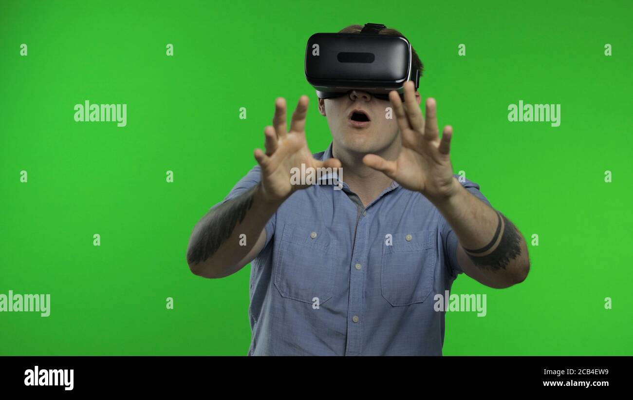 Stauned Mann mit VR App Headset Helm zu Simulationsspiel zu spielen, Zeichnung. Virtual Reality 3d 360-Video ansehen. Isoliert auf Chroma-Taste grünen Hintergrund im Studio. Kerl in VR-Brille, der sich umsieht Stockfoto