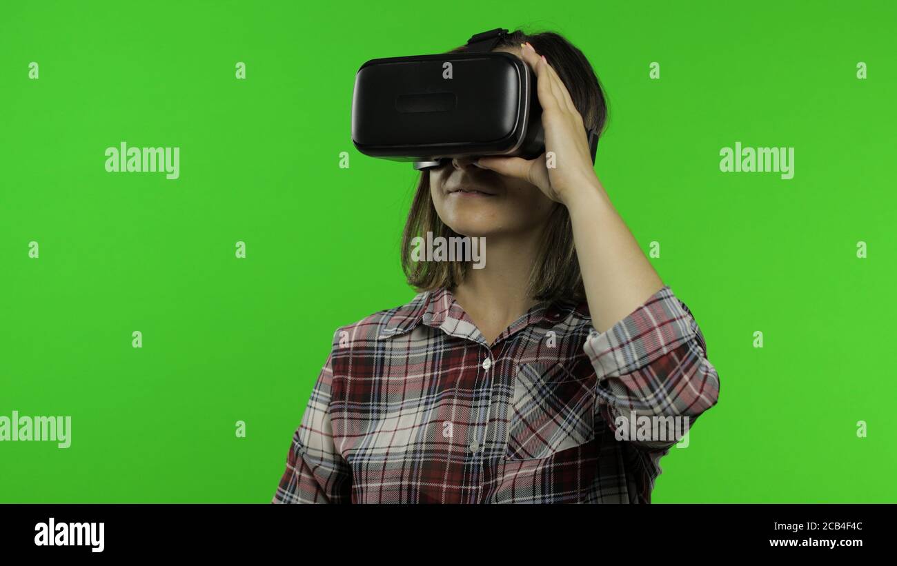 Junge Frau mit VR-App Headset Helm, um Simulationsspiel zu spielen. Virtual Reality 3d 360-Video ansehen. Isoliert auf Chroma-Taste grünen Hintergrund im Studio. Mädchen in VR-Brille, die sich umsieht, Daumen hoch Stockfoto