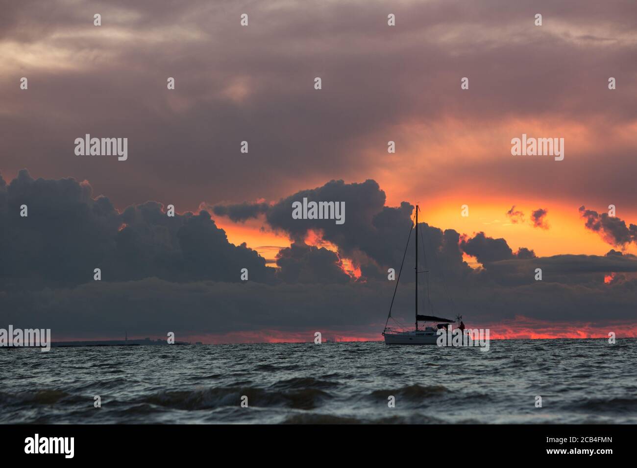 Segelboot bei Sonnenuntergang auf tropischem Meer, dramatischer Himmel im Hintergrund. Kreuzfahrt- und Yacht-Konzept Stockfoto