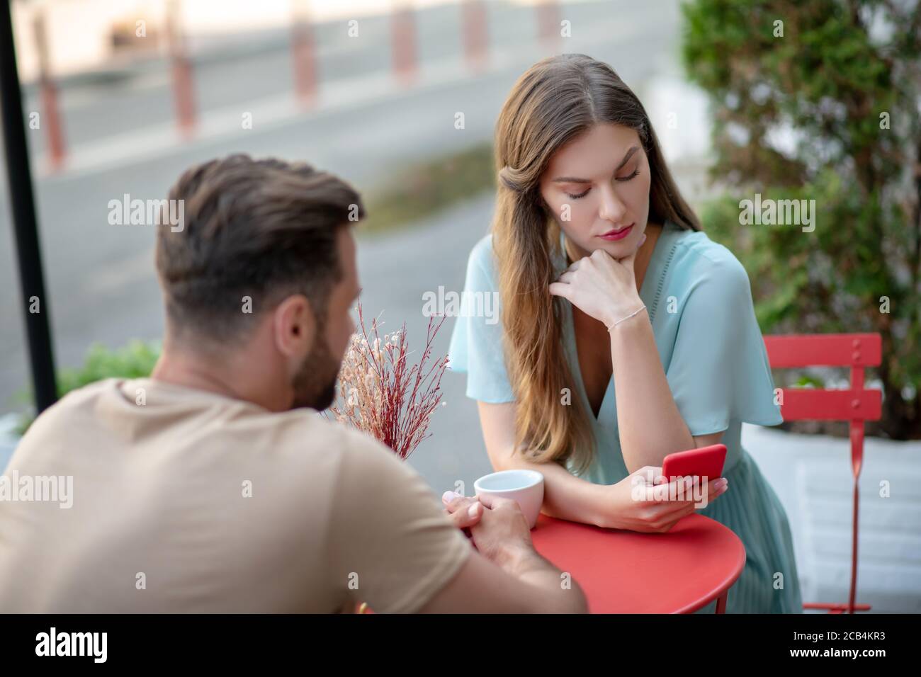 Das Paar hatte ein Missverständnis im Open-Air-Café, die Frau schaute auf ihr Telefon Stockfoto