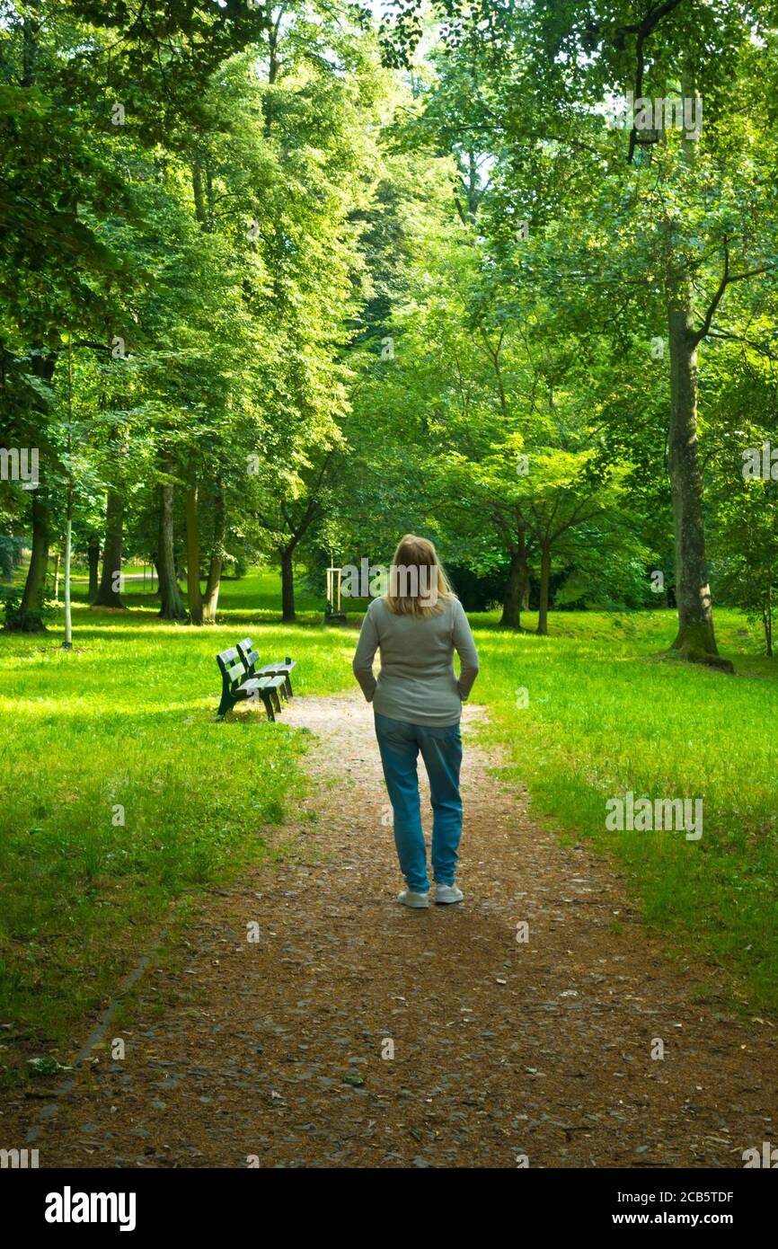 Blonde Frau steht in einem Park von Bäumen und Stille, Gemeinschaft mit der Natur und Seele suchen Konzept umgeben Stockfoto