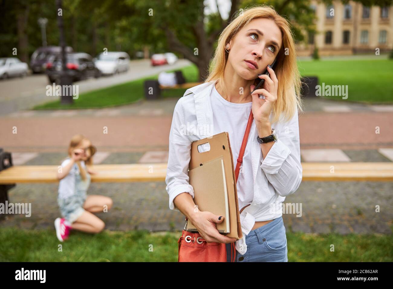 Verwirrt weiblich mit Ordner in der Hand, während im Stehen Stadtpark Stockfoto