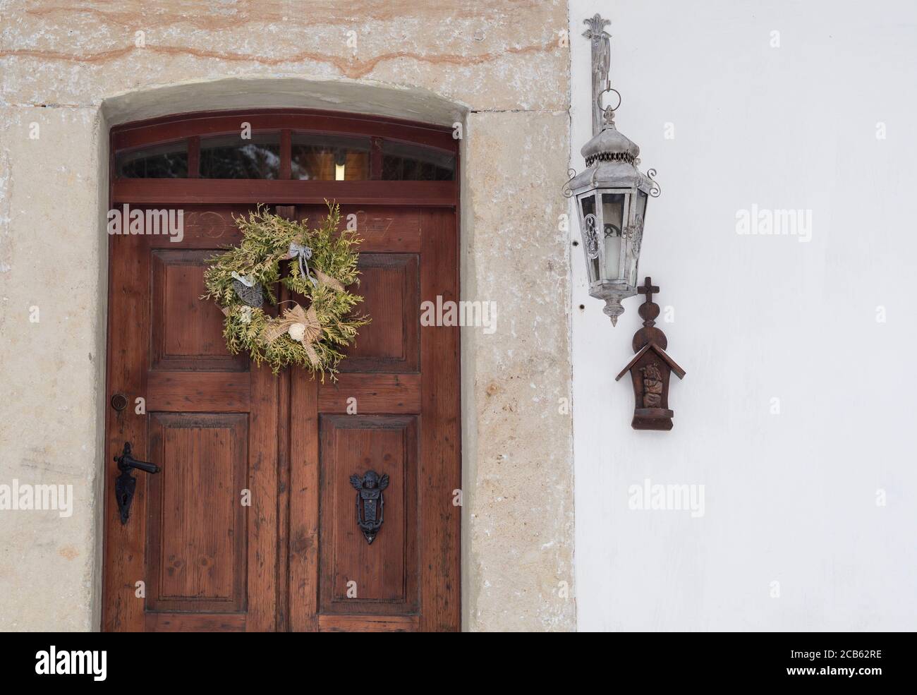 Alte Holztür mit Sandsteinverkleidung, Kranz, Laterne und Kreuz auf weißem Hintergrund Stockfoto