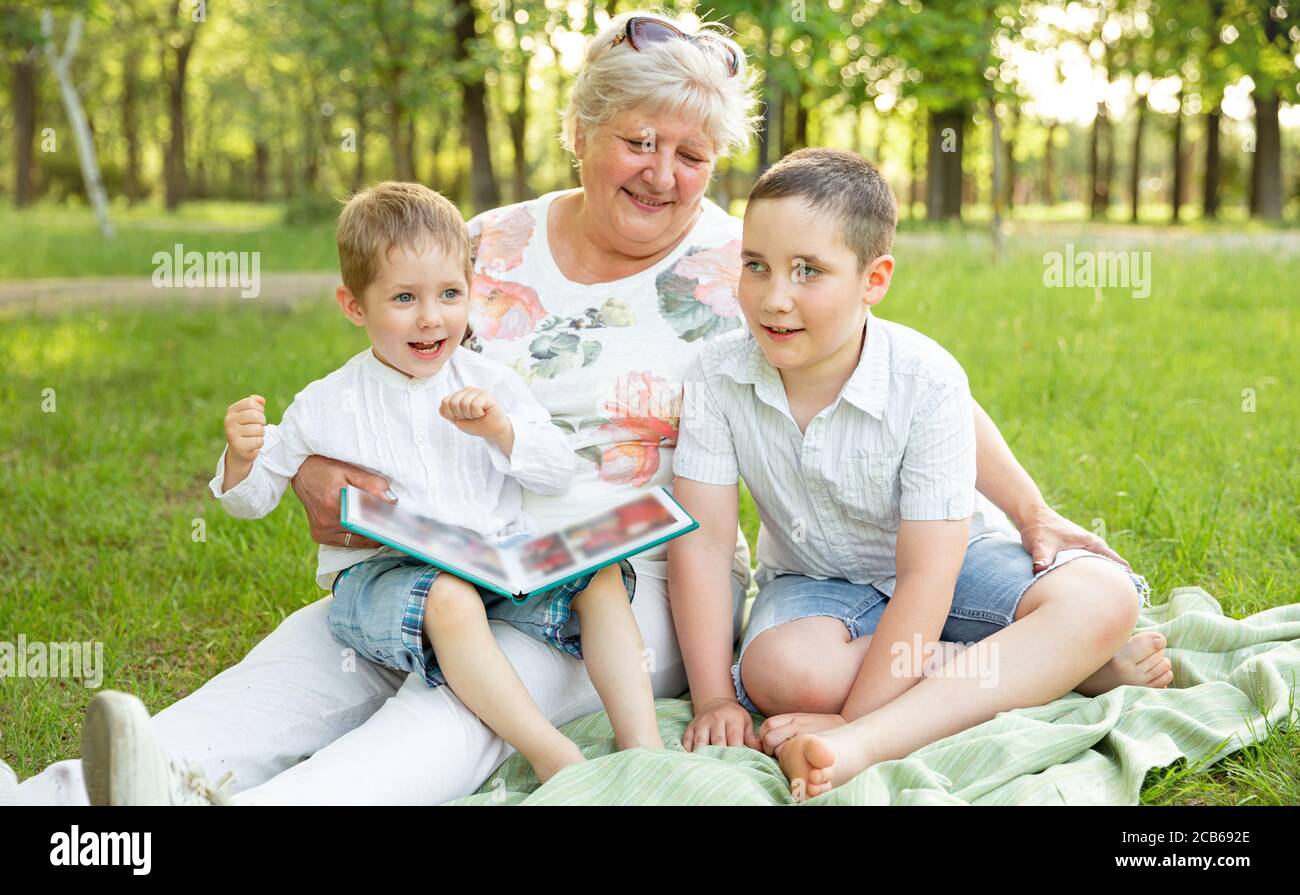 Kinder und Oma Spaß haben. Ältere Frau zeigt das Familienalbum Stockfoto