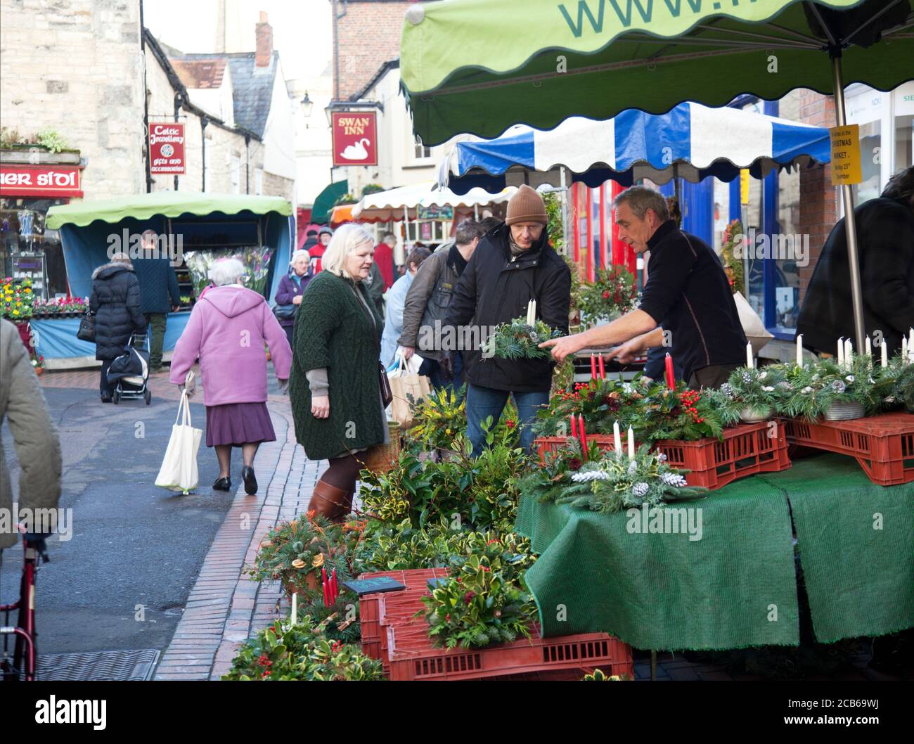 Einkäufer wählen Weihnachtsbäume Dekorationen Holly Beeren in einem Cotswold Famers Markt Stockfoto