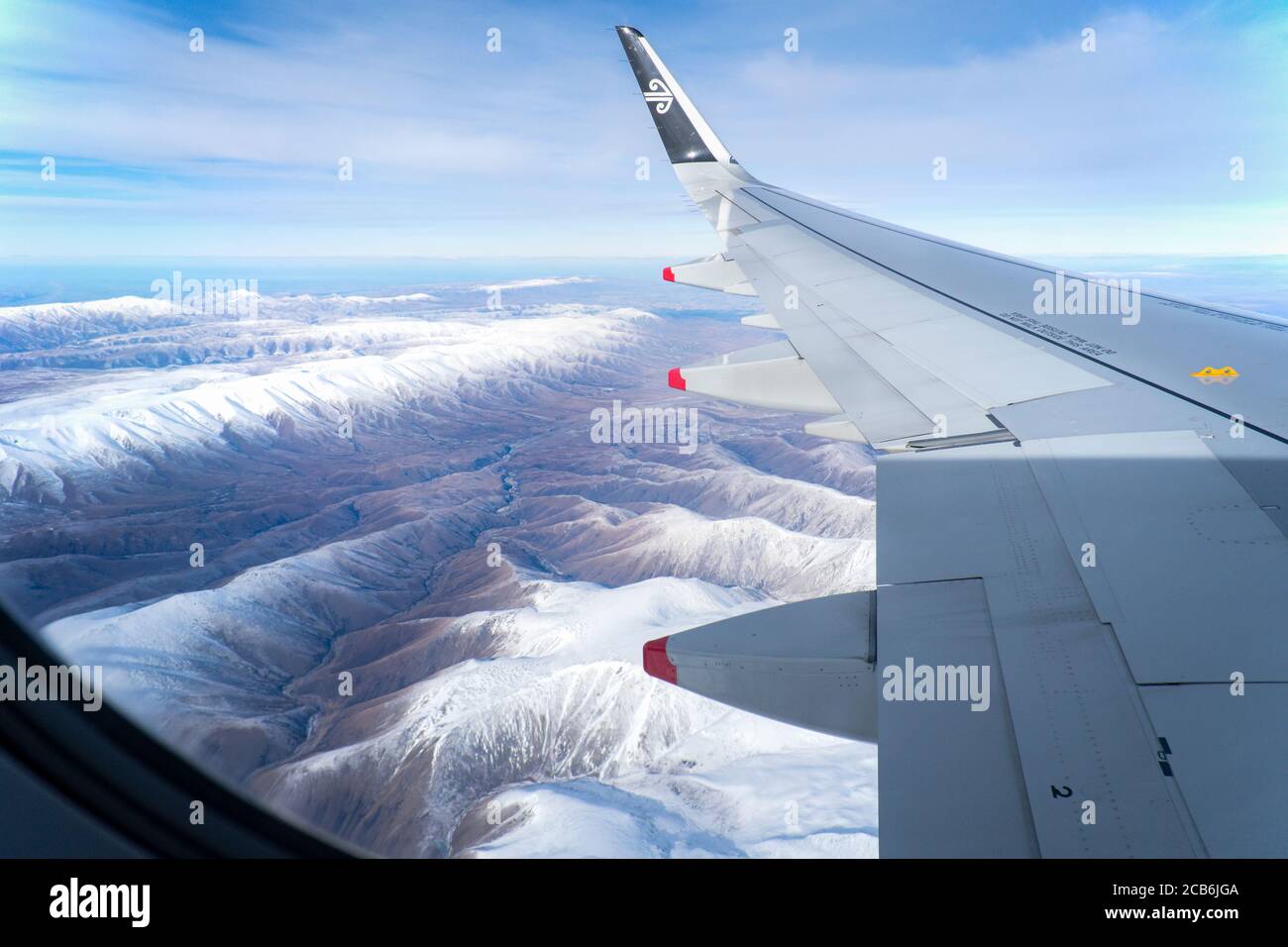 Luftaufnahme der schneebedeckten Bergketten im Winter von der Fenster eines Air New Zealand Fluges während des Fluges in Richtung Queenstown Stockfoto