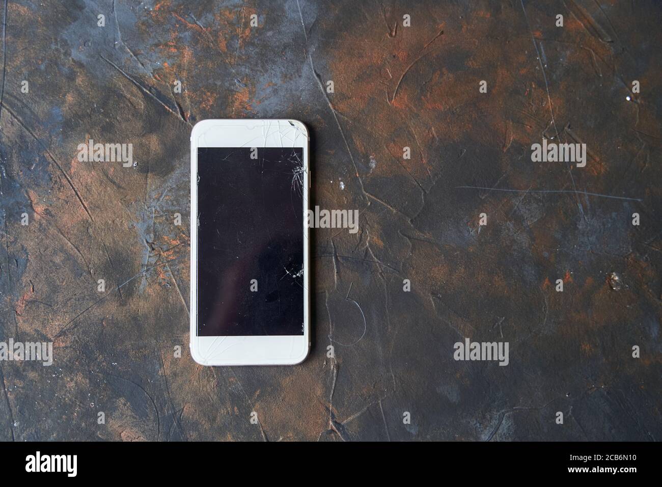 Weißes Telefon mit einem defekten Bildschirm auf dunklem Hintergrund Stockfoto