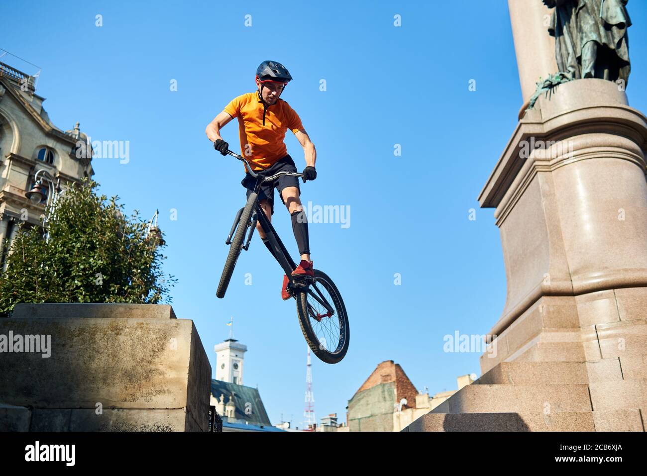 Blick von unten extremer Mann hält ein Sportfahrrad und hängt in der Luft. Radfahrer schaut nach unten, wenn er Trick macht. Konzept des Tricks. Stockfoto