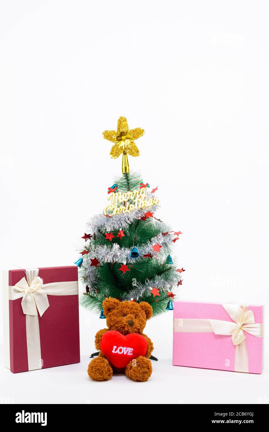 Teddybär mit Liebeszeichen und Weihnachtsgeschenke unter Weihnachten Baum mit fröhlichen Weihnachtsschreiben Stockfoto