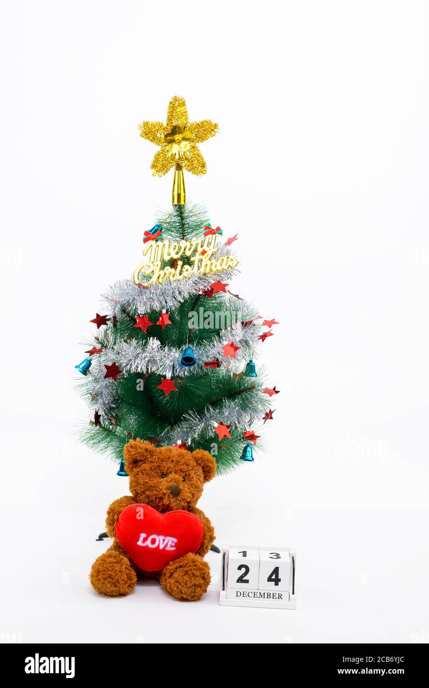 Geschmückter Weihnachtsbaum mit fröhlicher Weihnachtsschrift und Teddybär Mit Herz neben dem 24. Dezember Kalender Stockfoto