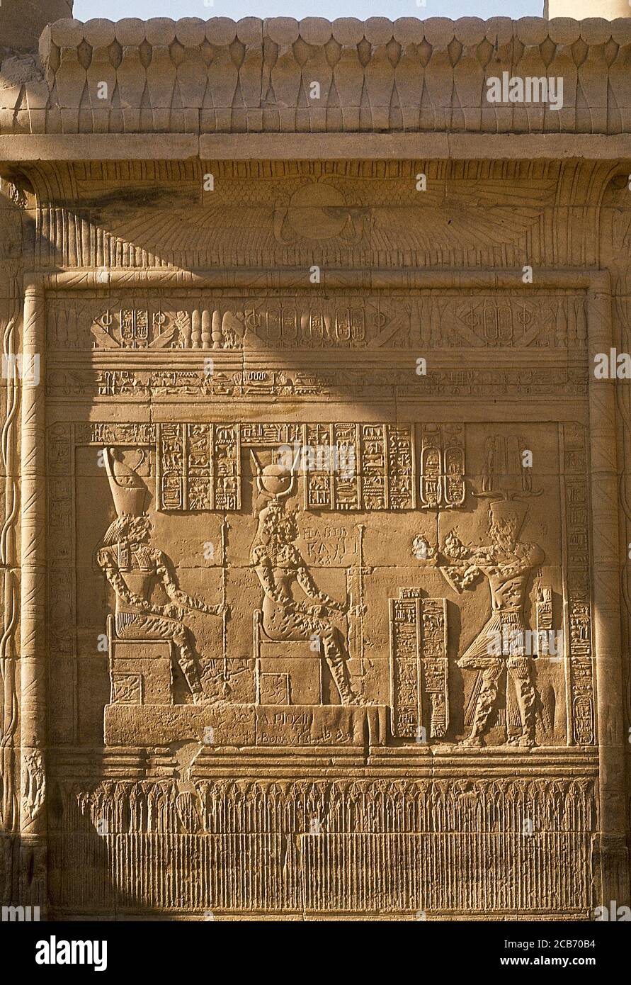 Ägypten, Philae. Reliefs an einer Wand des Tempels von Isis. Darbietszene dem gott Horus (Falkenköpfchen) und der Göttin Isis (Sonnenschale). Unterer Streifen, der Lotusblumen darstellt. Stockfoto