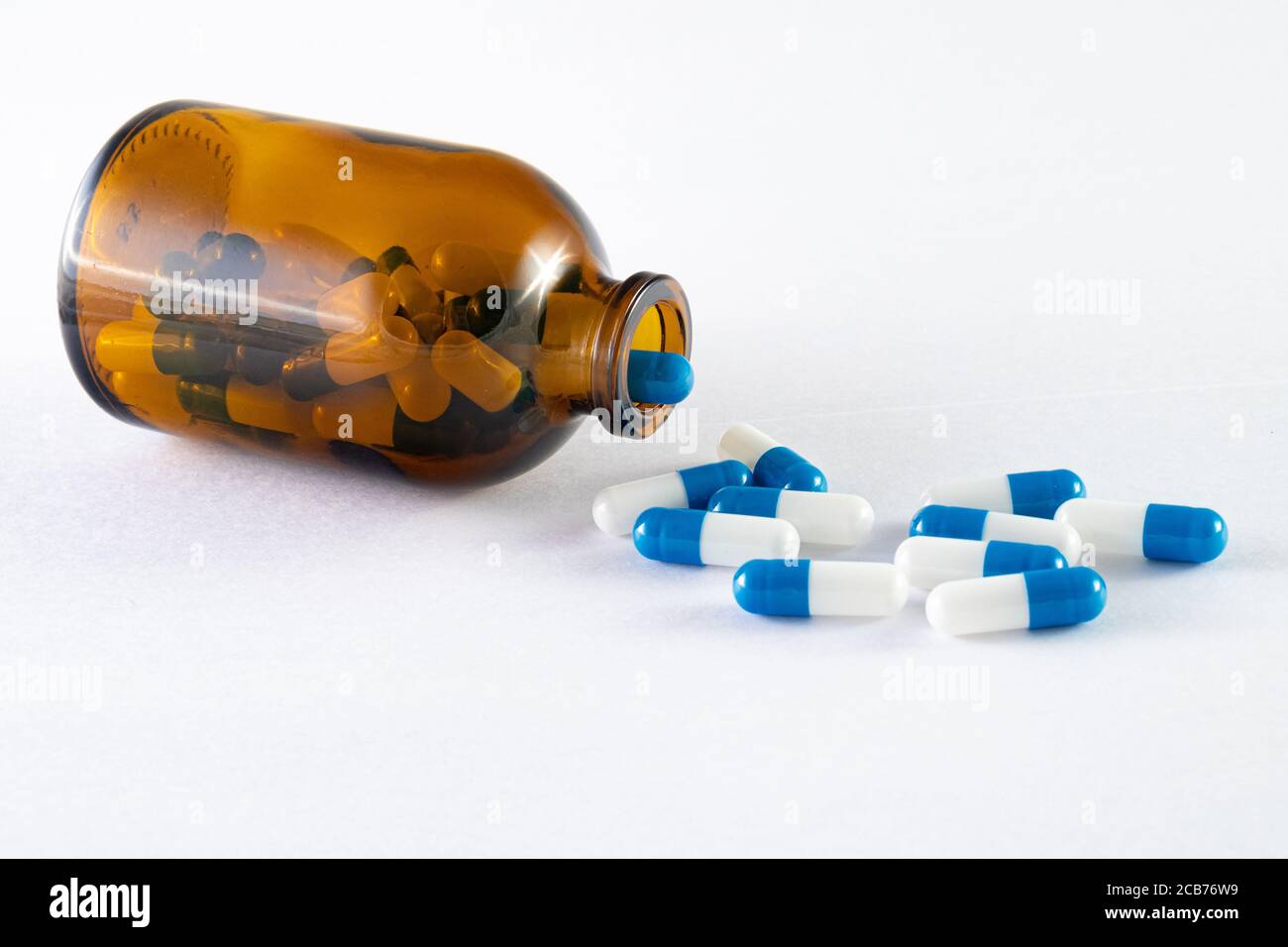 Medicine Tabletten innen und außen eine bernsteinfarbene Glasflasche auf weißem Hintergrund. Stockfoto