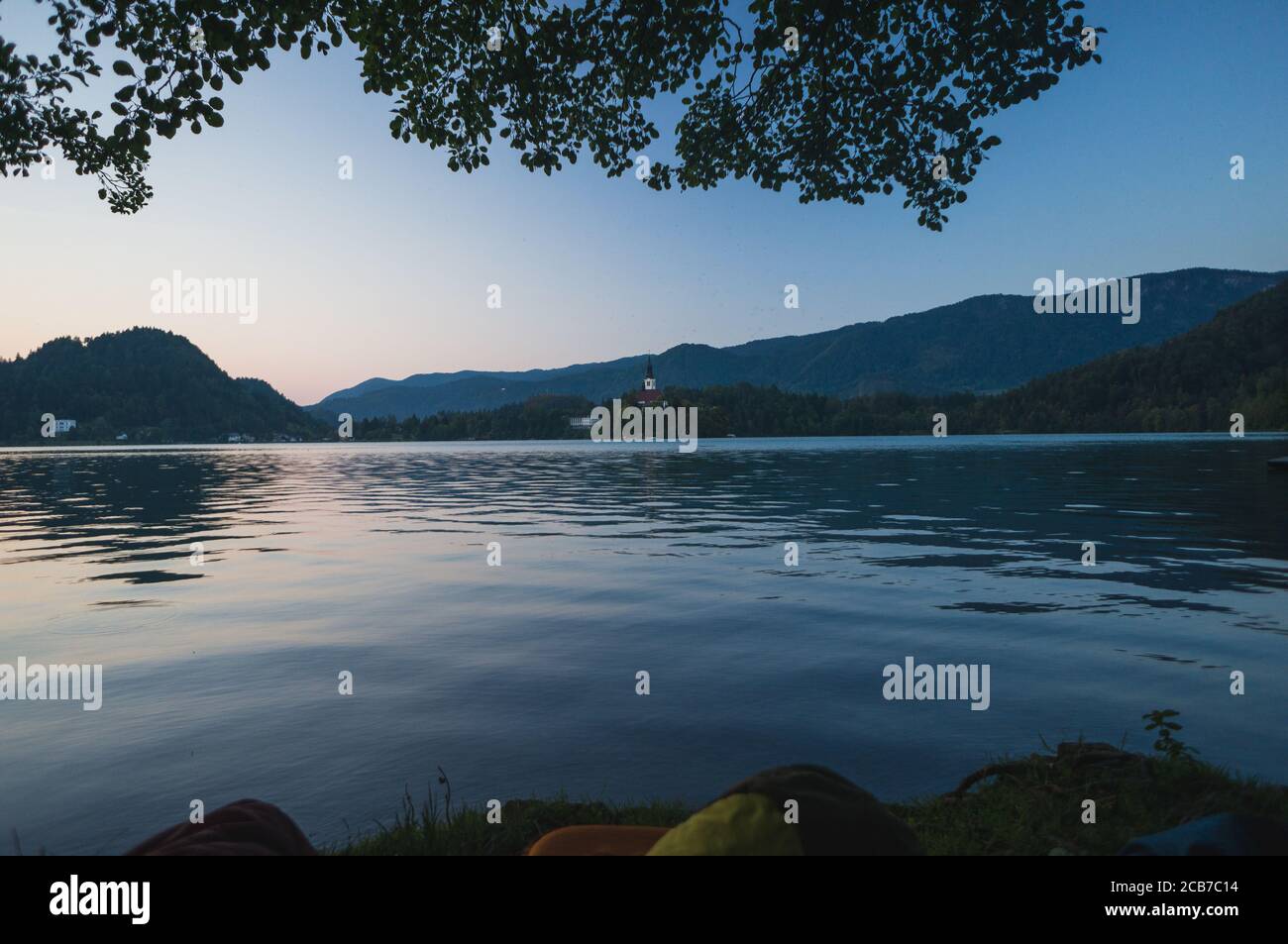 Am frühen Morgen See Bled in Slowenien. Ruhiger See, aufgehende Sonne hinter den Bergen, Alpen. Schlafsäcke im Vordergrund, Outdoor-Abenteuer im Trigl Stockfoto