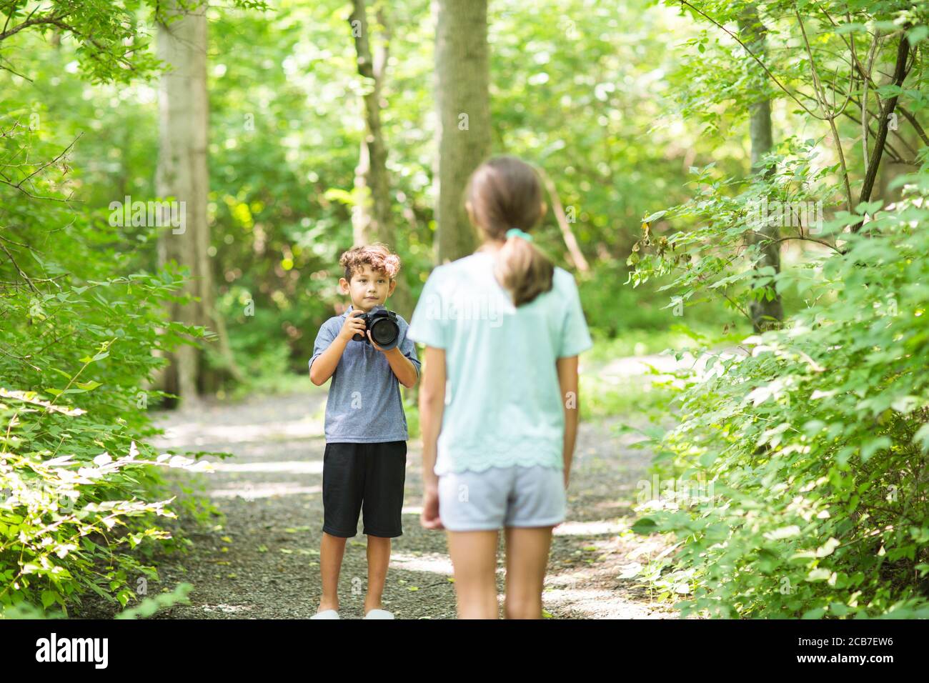 Kleiner Junge, der seine Schwester im Wald fotografieren ließ. Stockfoto