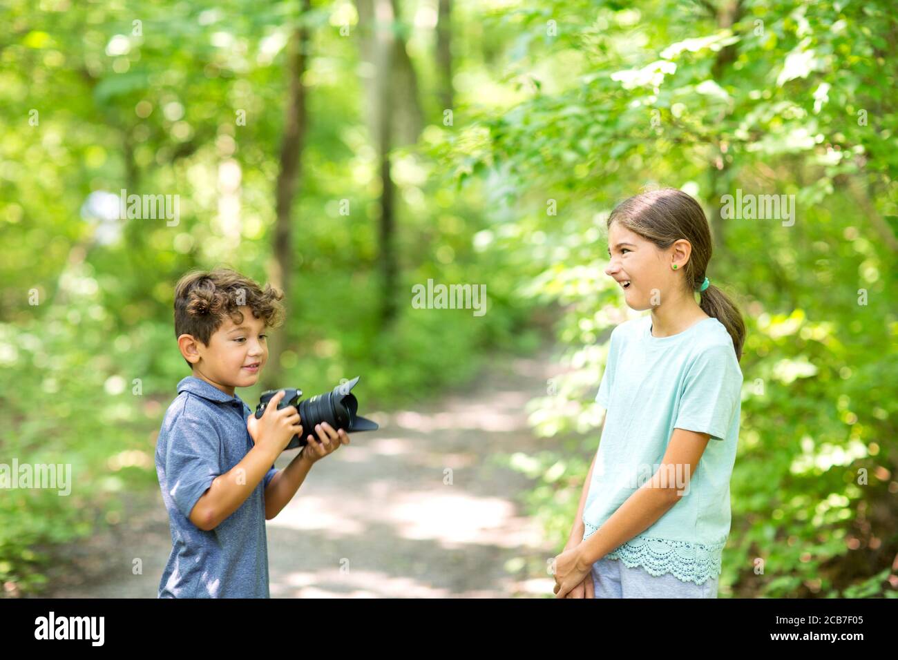Kleiner Junge, der seine Schwester im Wald fotografieren ließ. Stockfoto