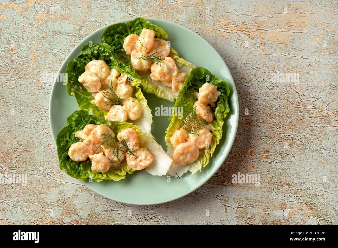 Garnelen auf Salatblättern in einem grünen Teller und rustikal Hintergrund Stockfoto