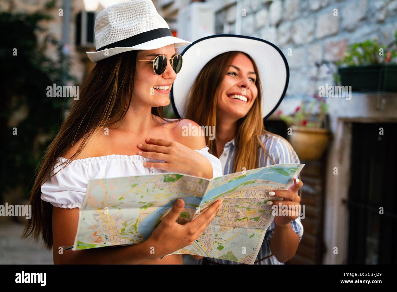 Glückliche junge Frauen mit Karte in der Stadt. Reise Touristen Leute Spaß Konzept. Stockfoto