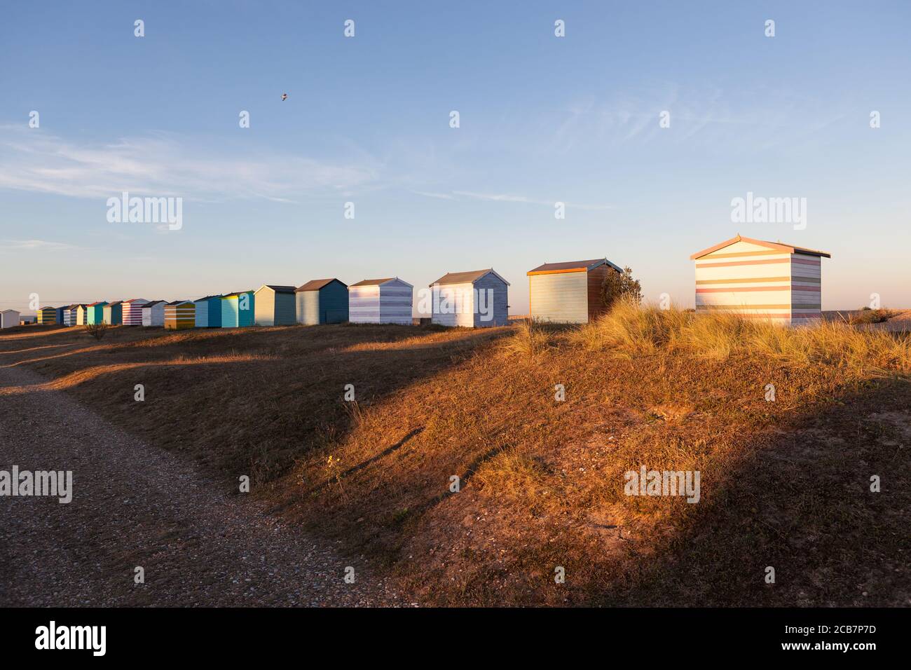 Die untergehende Sonne trifft auf die Rückseite von einigen englischen Strandhütten an einem Strand in Kent. Stockfoto Die untergehende Sonne trifft auf die Rückseite von einigen englischen Strandhütten an einem Strand in Kent. Stockfoto