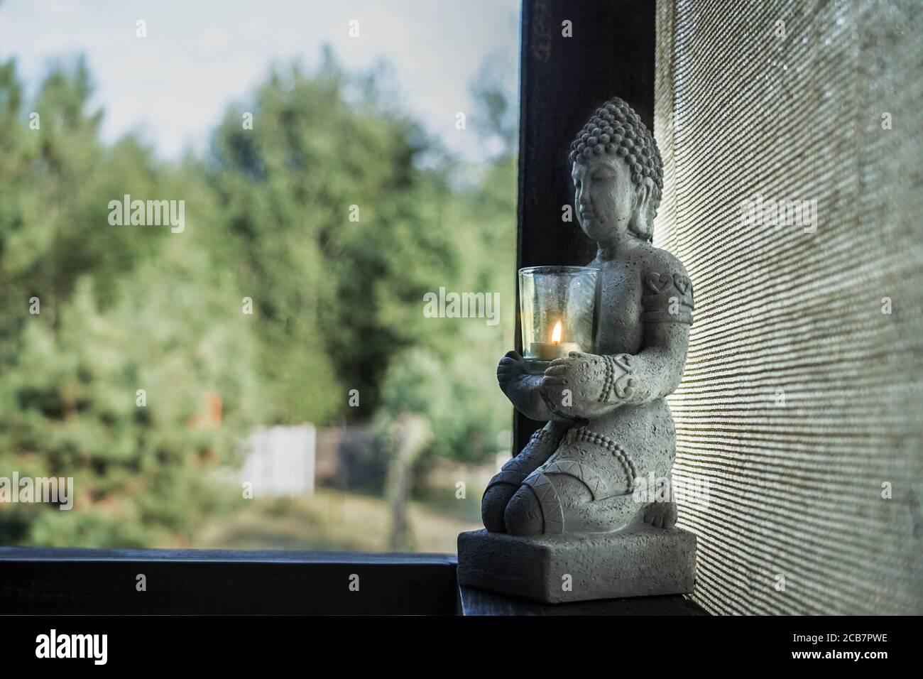 Statue eines buddha mit einem Kerzenständer auf einem Holzfensterbank Stockfoto