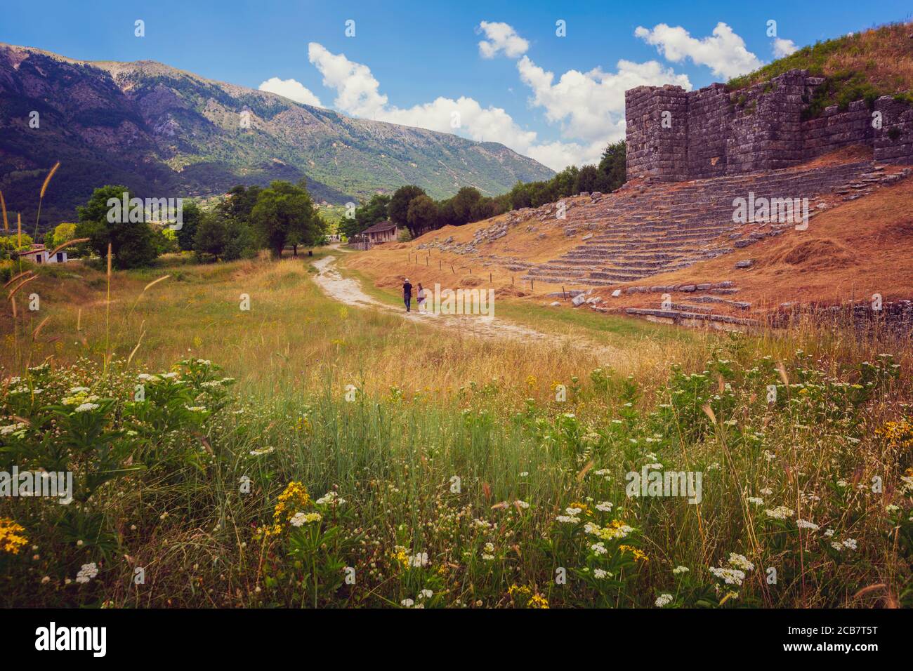 Griechenland, Epirus. Ein Paar schlendert durch die Ruinen des alten Dodoni. Die Wände des Theaters rechts. Stockfoto