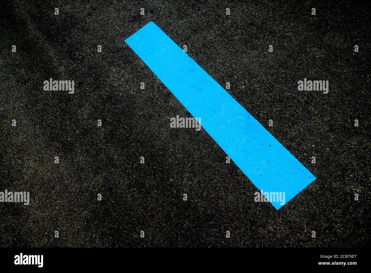 Breites diagonales blaues Band auf einer asphaltierten schwarzen Oberfläche. Stockfoto