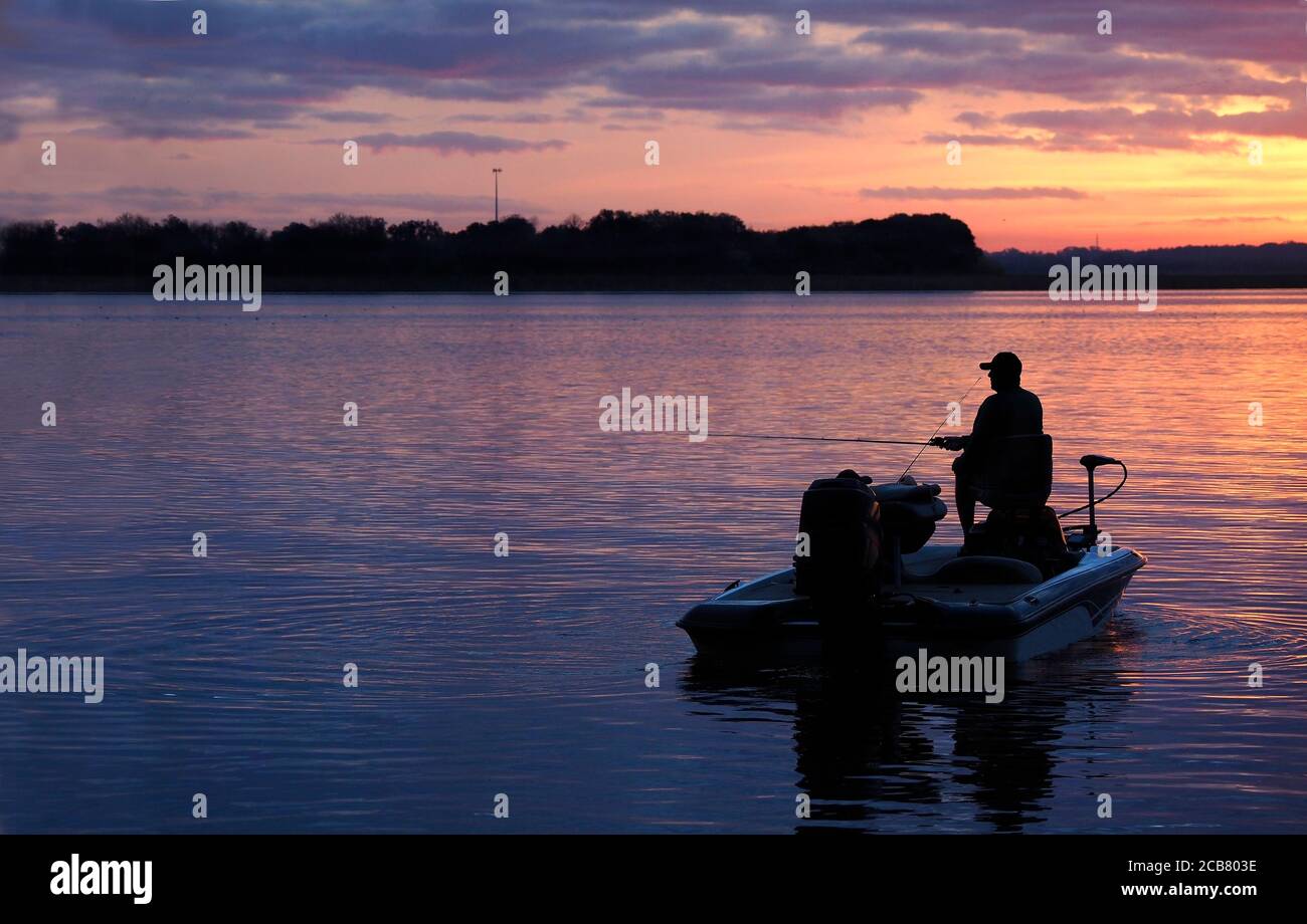 Silhouette eines nicht erkennbaren Fischers Angeln, wie die Sonne kommt Oben in einem wunderschönen Sonnenaufgang Stockfoto