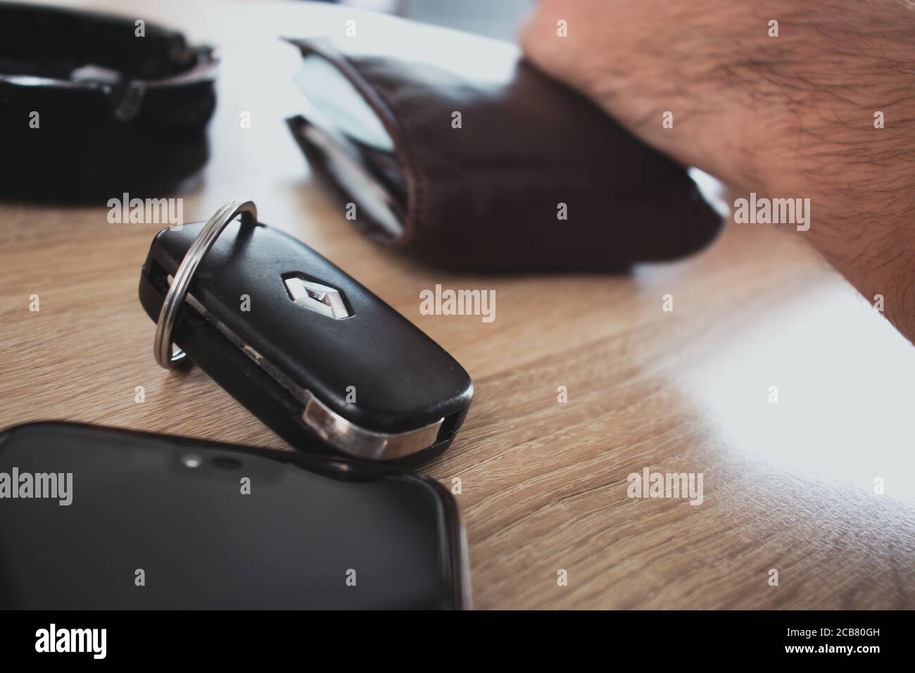 Supetar, Kroatien August 2020 Autoschlüssel aus einem Renault Clio, Geldbörse und Telefon auf einem Holztisch. Menschen, die ihre Taschen beim Sitzen leeren Stockfoto